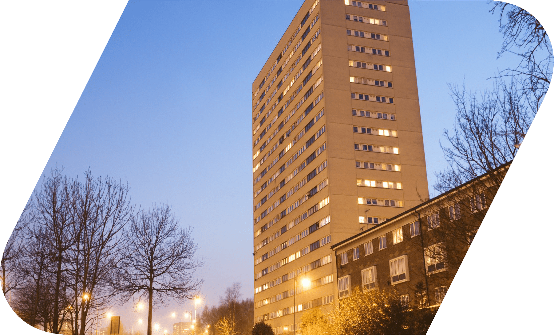 A picture of a residential building at dawn with lights on.